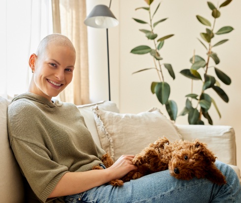 Cancer patient sitting on couch with puppy