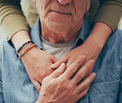 Supportive family member hugging elderly man
