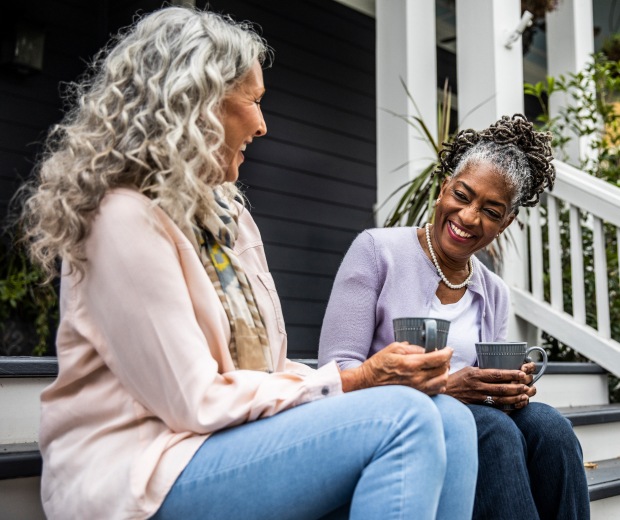 neighbors drinking coffee together on porch steps