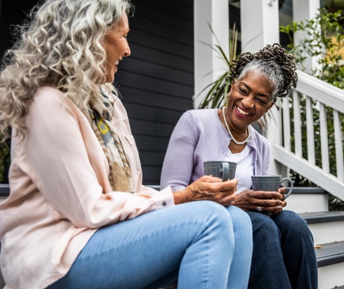 neighbors drinking coffee together on porch steps