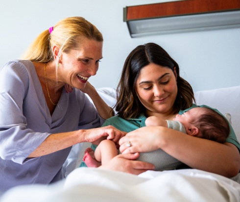 Woman and mother admiring newborn baby in birth center room
