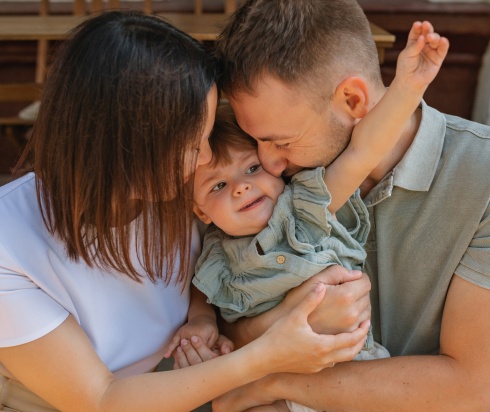 Parents hugging and kissing their child