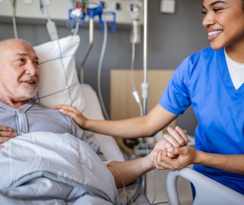 Nurse and patient holding hands in hospital room
