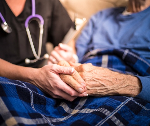 Nurse holding elderly patient's hands