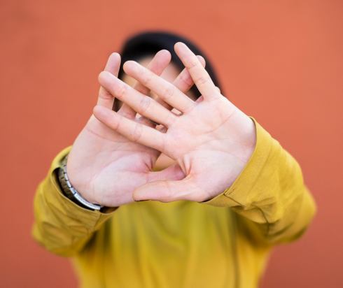 Person holding hands up to block their face